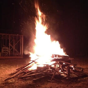 A bonfire at night. The image is high contrast, with the flames mostly appearing white.